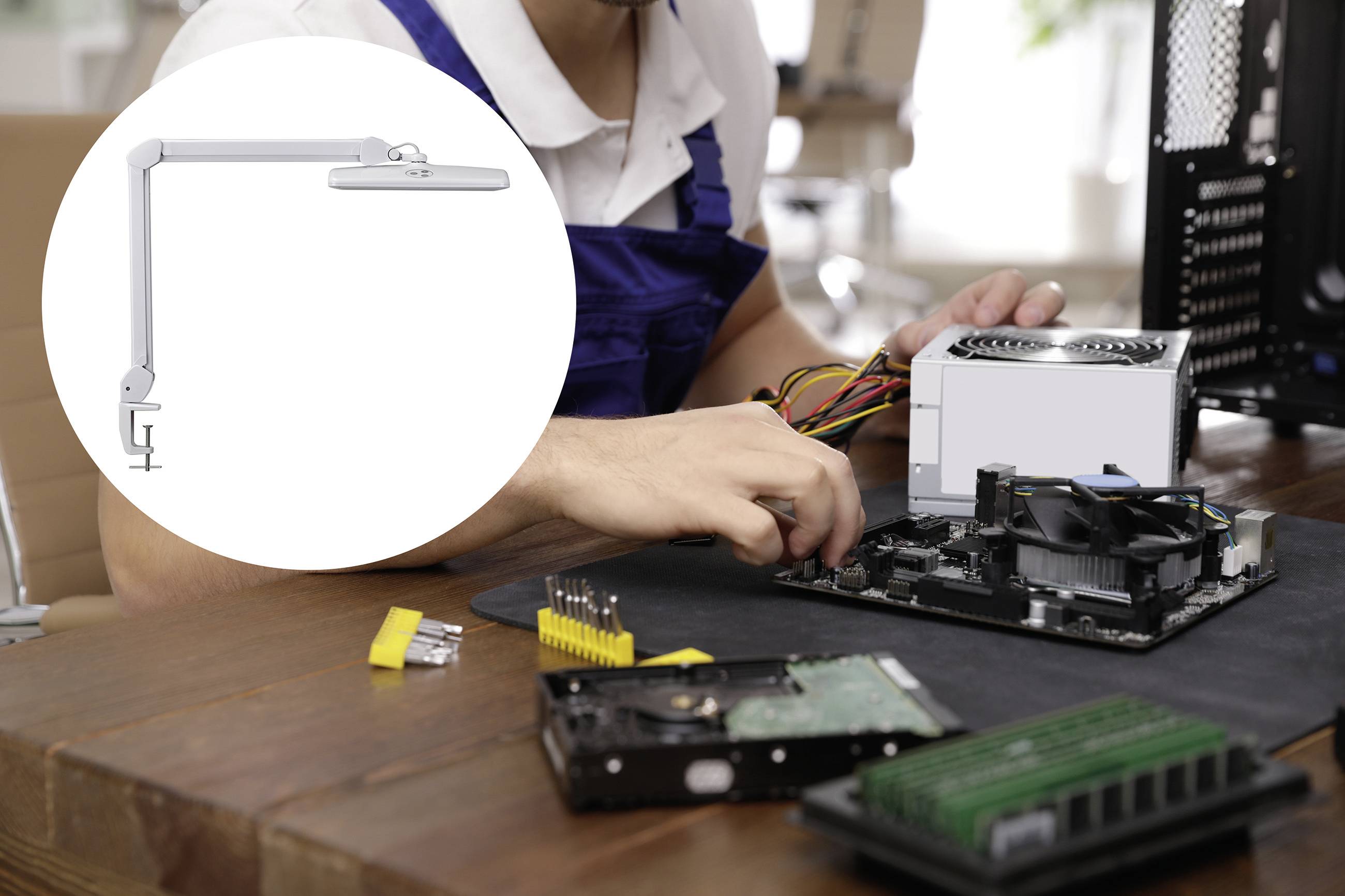 Ein Techniker montiert Computerkomponenten auf einer Werkbank. Im Hintergrund eine Arbeitsleuchte zur Befestigung an Tischen.