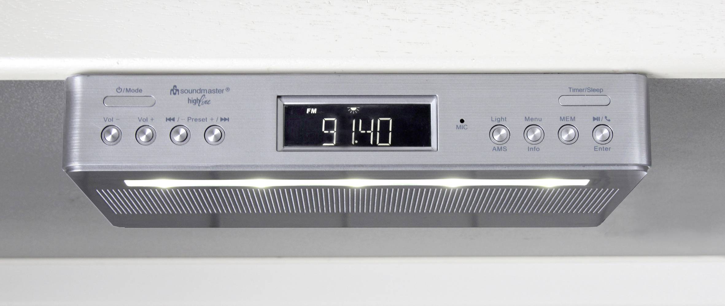 Ein Unterbau-Radiogerät mit digitalem Display zeigt die Uhrzeit 9:14 an. Es hat Tasten für Einstellungen und Lautstärke.