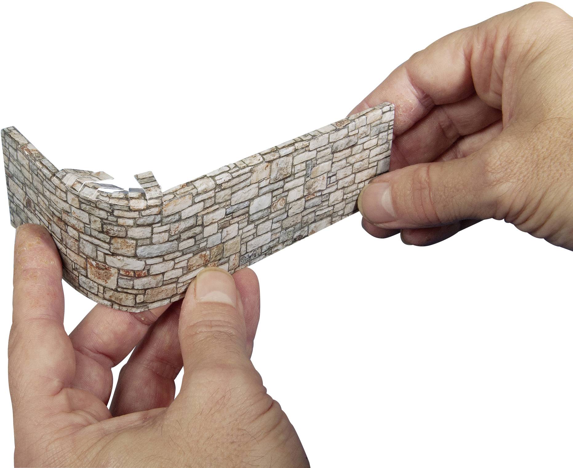 Zwei Hände halten ein kleines Modell einer gemauerten Wand. Die Wand ist gebogen und besteht aus hellen, rechteckigen Steinen.