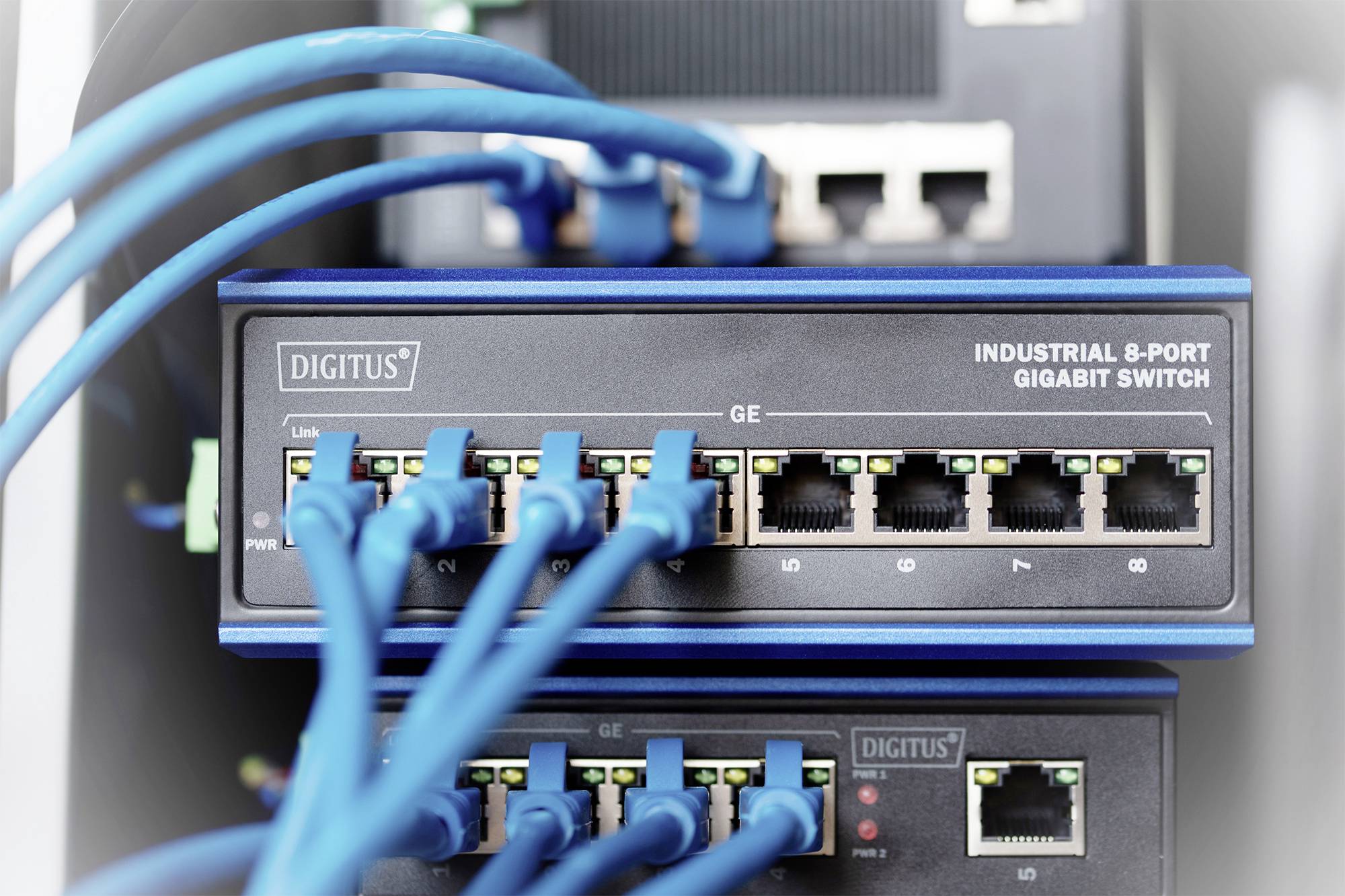 Ein 'Industrial 8-Port Gigabit Switch' mit mehreren blauen Ethernet-Kabeln, die angeschlossen sind, in einem Server-Rack.