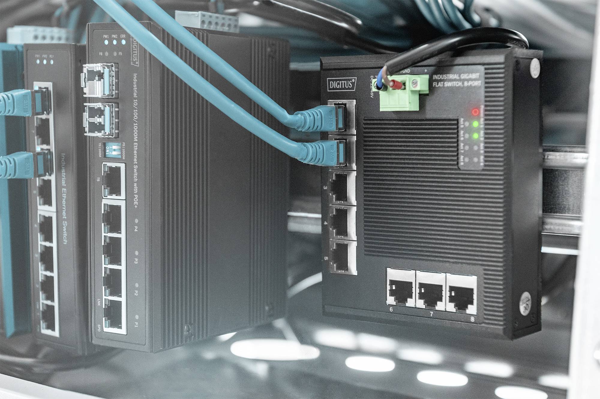 Netzwerkgeräte mit mehreren Kabel- und Anschlussverbindungen in einem Serverraum. LEDs leuchten an der Vorderseite der Geräte.