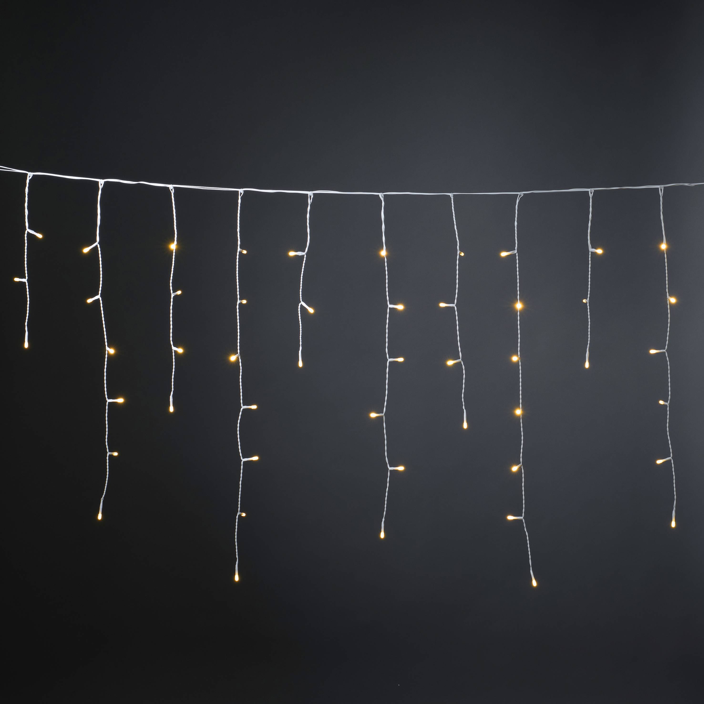 Lichterkette mit warmweißen LEDs hängt vor einem dunklen Hintergrund.