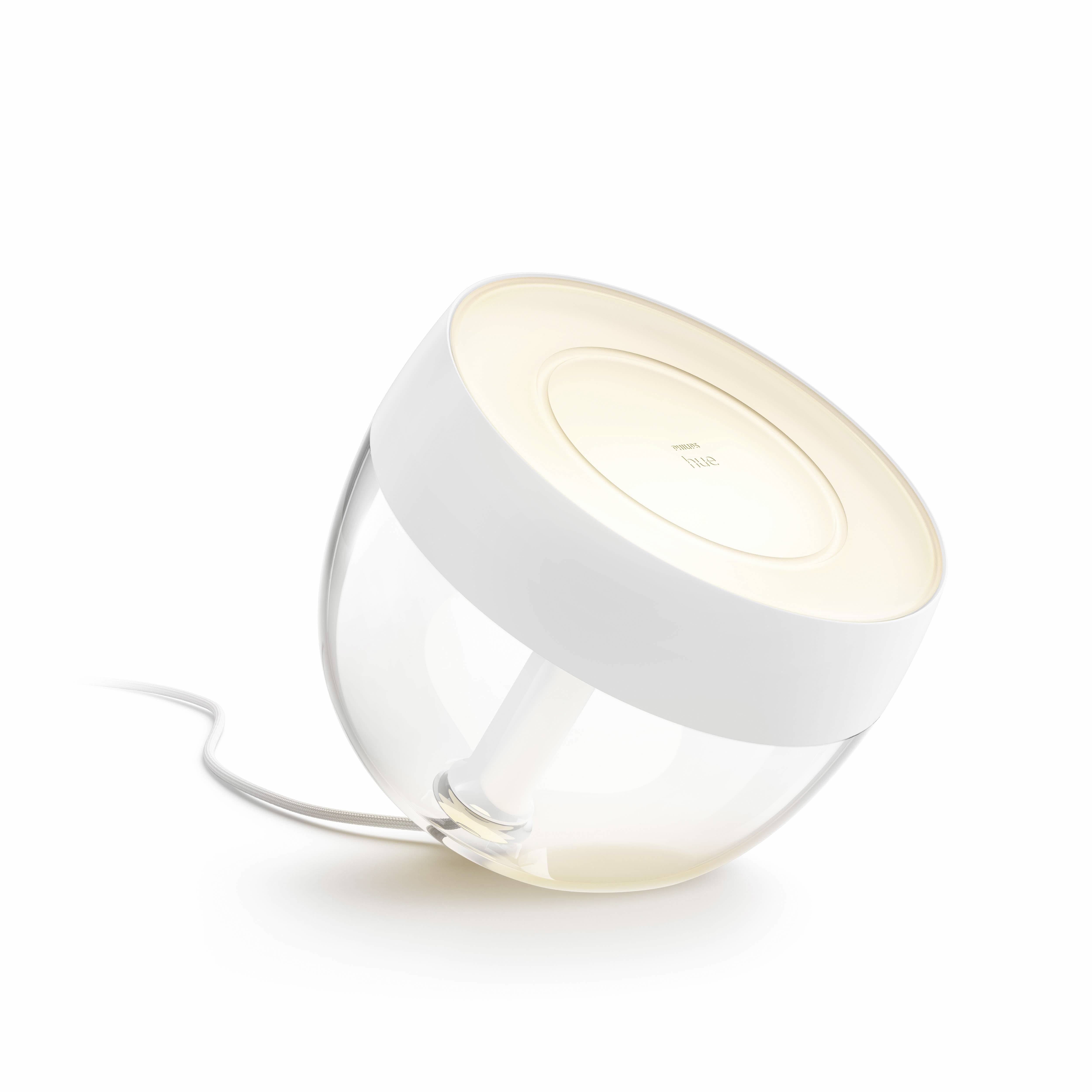 Runde, moderne Tischlampe mit weißem Rahmen und transparentem Glas. Sie gibt warmes, weiches Licht ab und ist schräg positioniert.