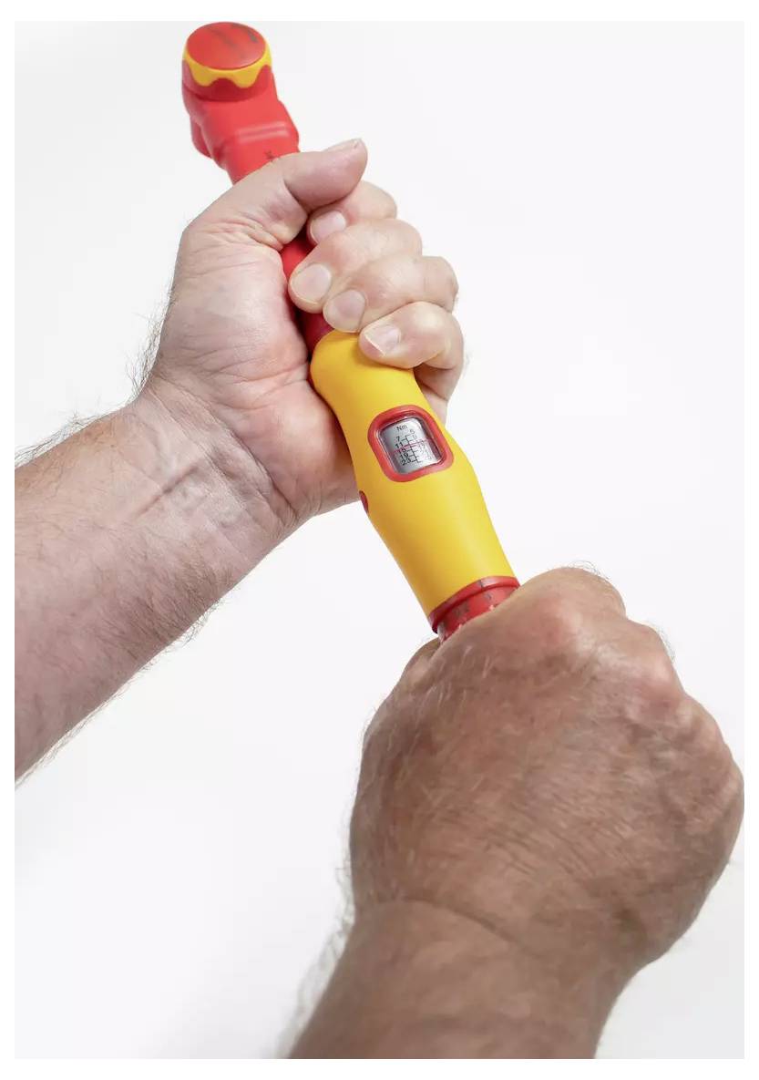 Eine Person, die ein gelbes und rotes Werkzeug ergreift, ähnlich einem tragbaren Schraubenschlüssel, und mit beiden Händen eine Drehbewegung demonstriert.