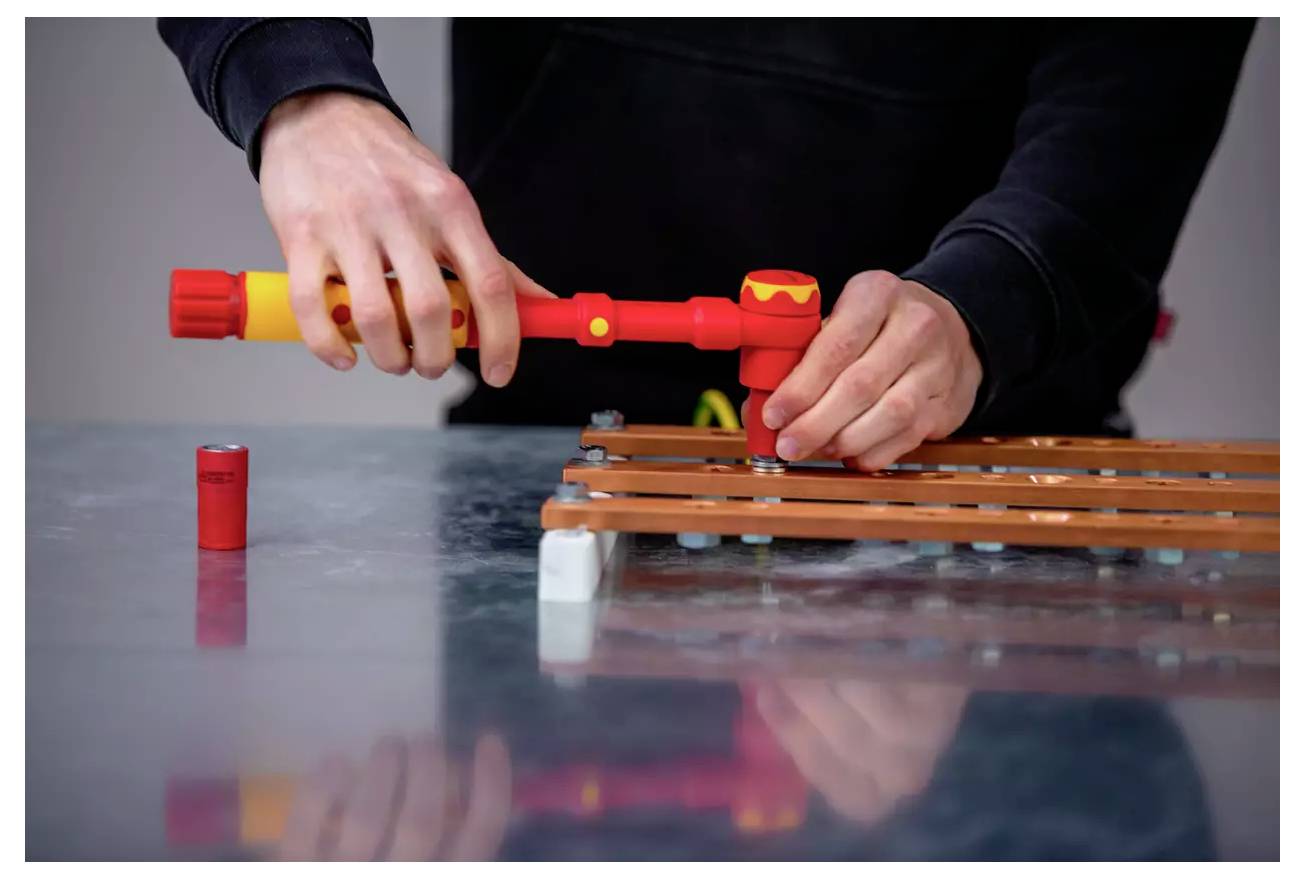 Person, die ein isoliertes Werkzeug an einer elektrischen Komponente verwendet und dabei die Sicherheit während Wartung oder Montage gewährleistet.