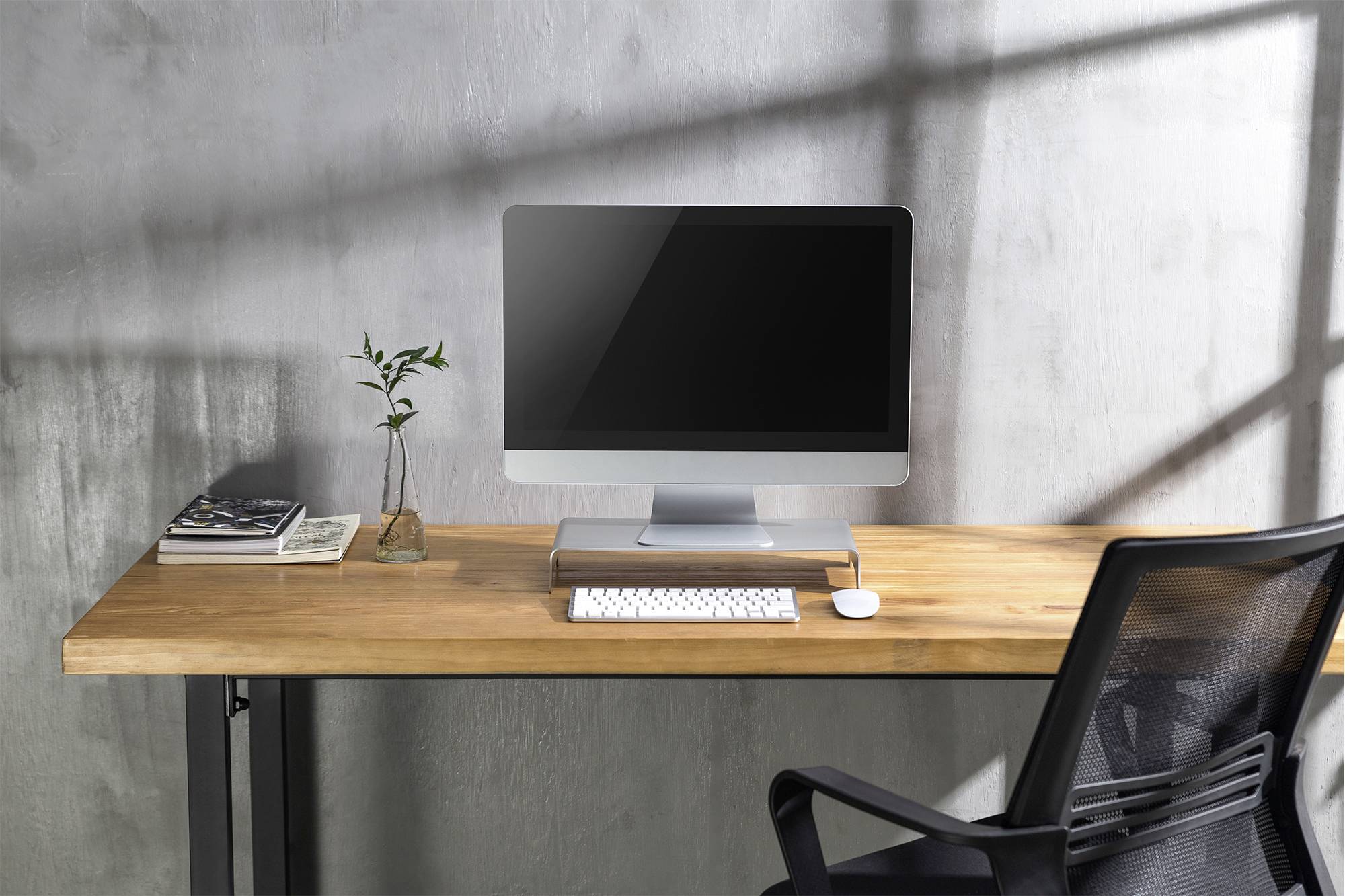 Ein moderner Computertisch mit einem Desktop-Computer, Tastatur, Maus, Pflanzenvase und Büchern auf einem hölzernen Schreibtisch.