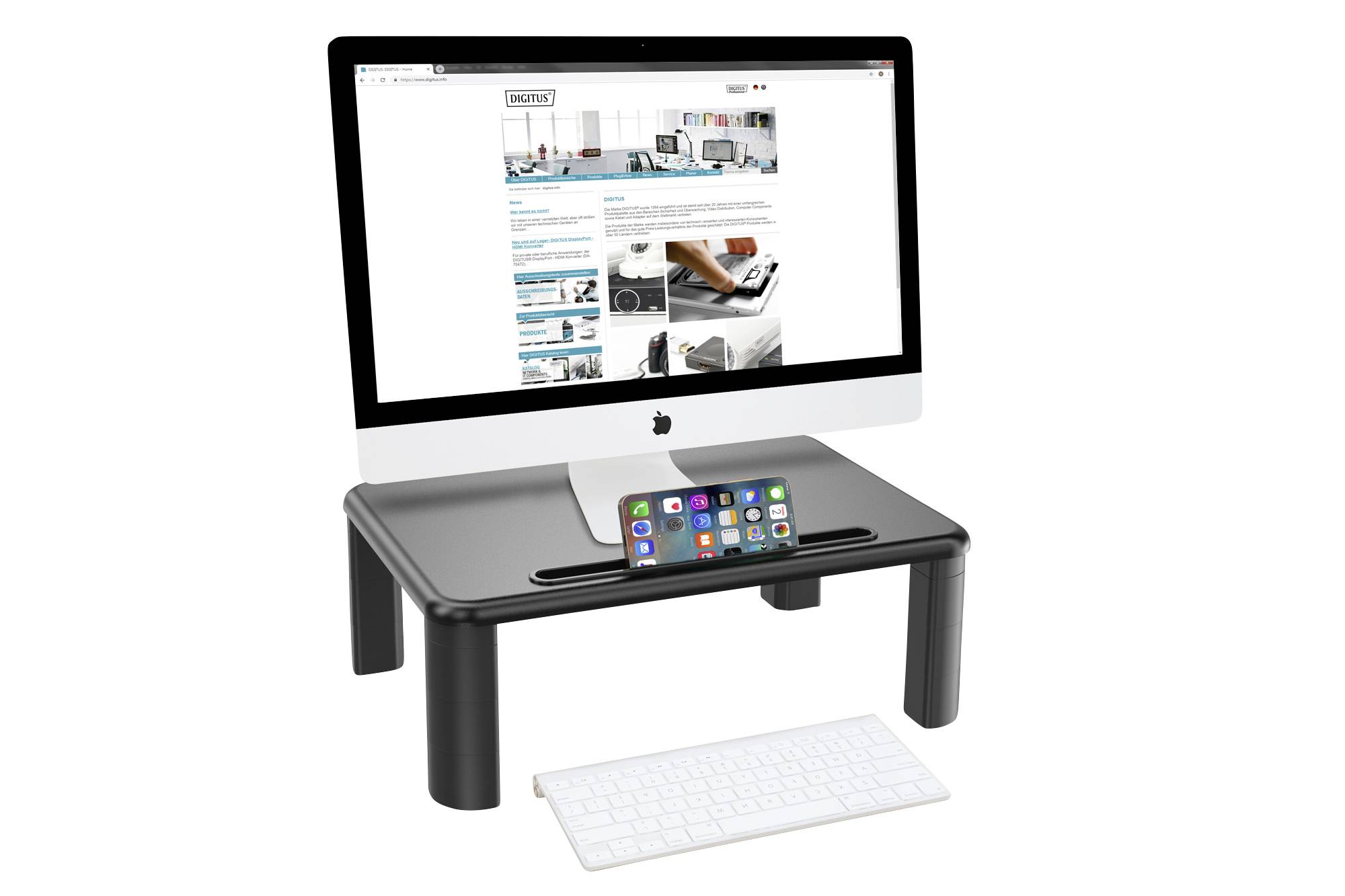 Ein Computerbildschirm auf einem Monitorständer, darunter eine Tastatur. Ein Smartphone steht aufrecht im Ständer. Bildschirm zeigt eine Webseite.