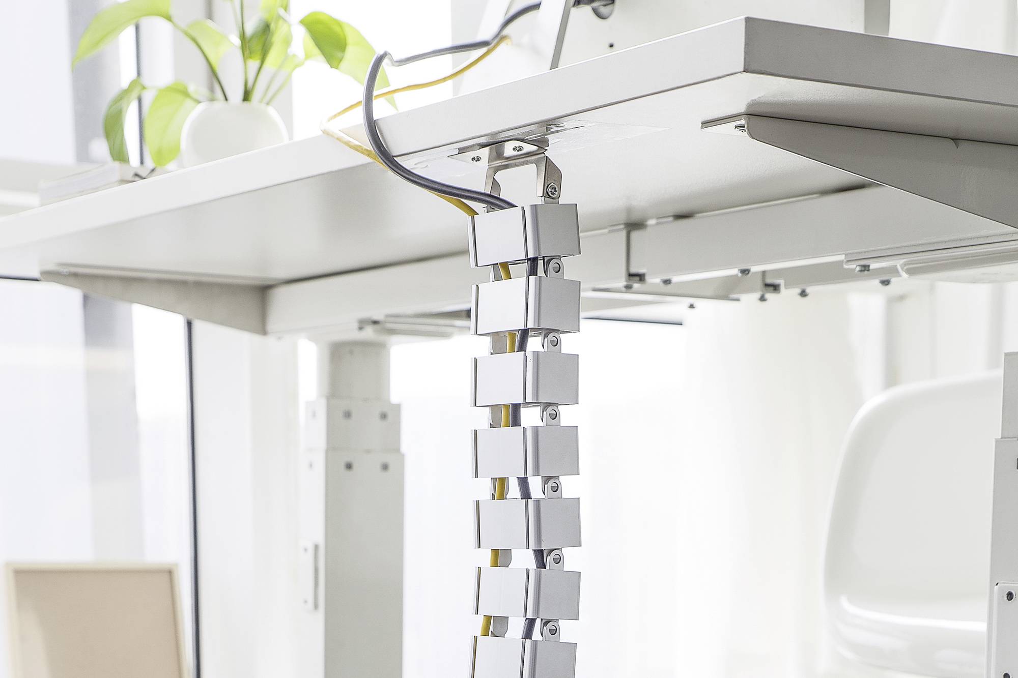 Ein Schreibtischkabelmanagementsystem, das flexible Kabelhalterungen zeigt, um Kabel ordentlich unter einem Bürotisch zu organisieren.