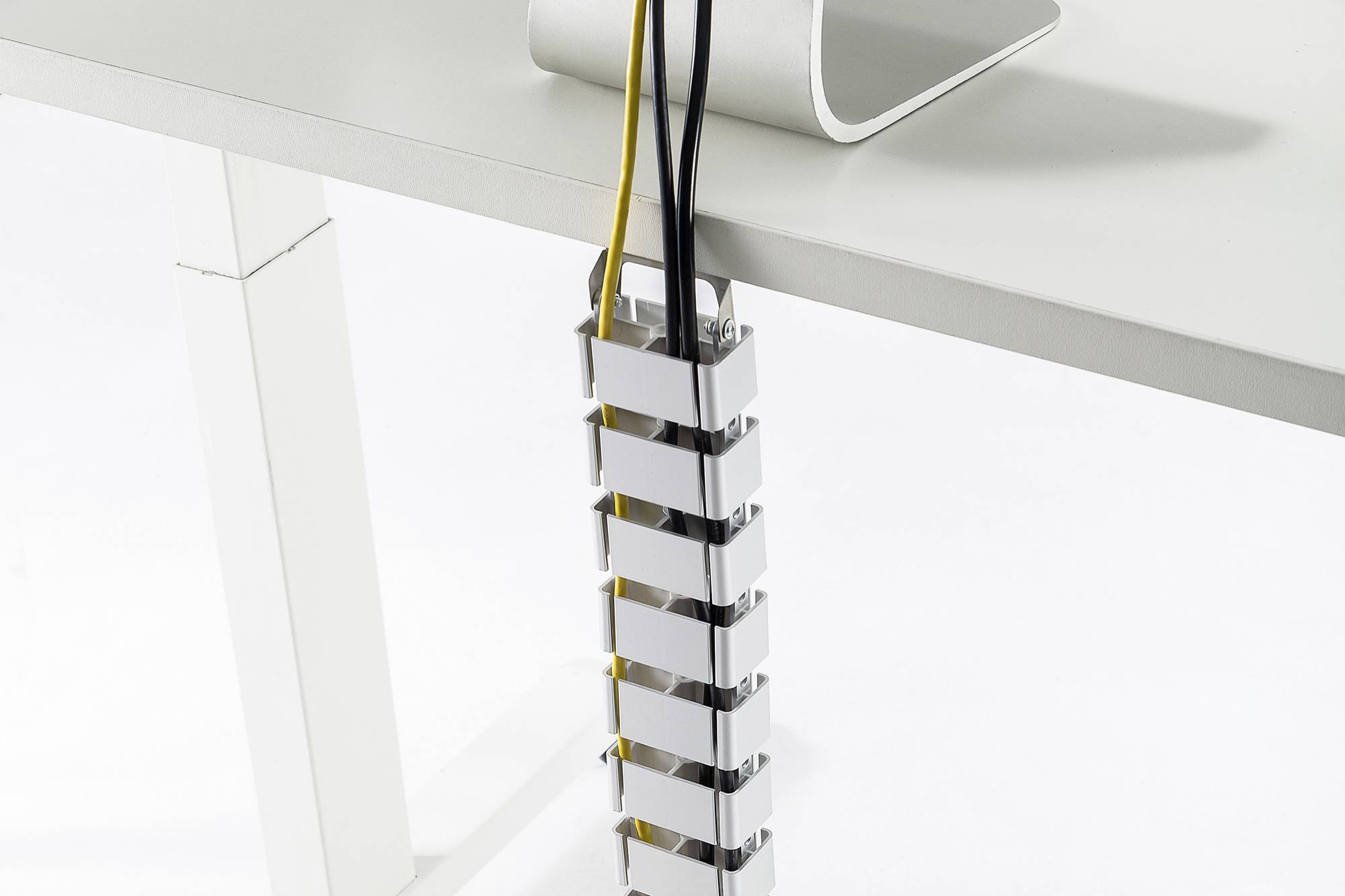 Kabelmanagement-System hält mehrere Kabel organisiert und sicher entlang eines weißen Tischbeins.