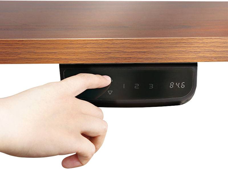 Eine Hand drückt auf eine digitale Steuerung unter einem Holztisch, die Höhenverstellung und Display mit der Anzeige '84.6' zeigt.