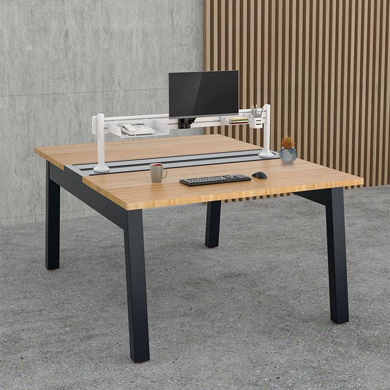 Ein moderner Schreibtisch in einem Büro, ausgestattet mit einem Monitor, Tastatur, Maus, Kaffeetasse und kleinem Pflanzenarrangement.