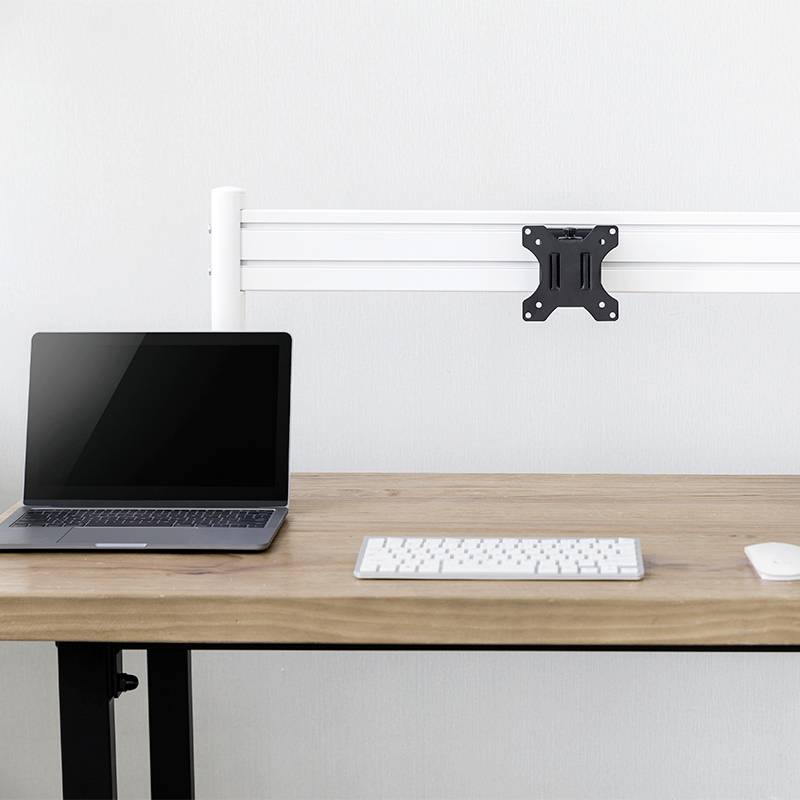 Ein Laptop und eine Tastatur auf einem Holztisch, daneben eine leere Wandhalterung.