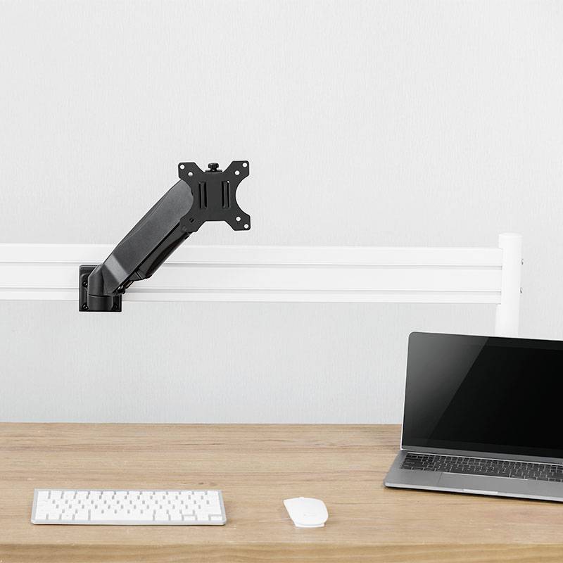 Ein leerer Monitorarm steht an einem Schreibtisch mit einer Tastatur, einer Maus und einem geöffneten Laptop, alles in minimalistischer Umgebung.