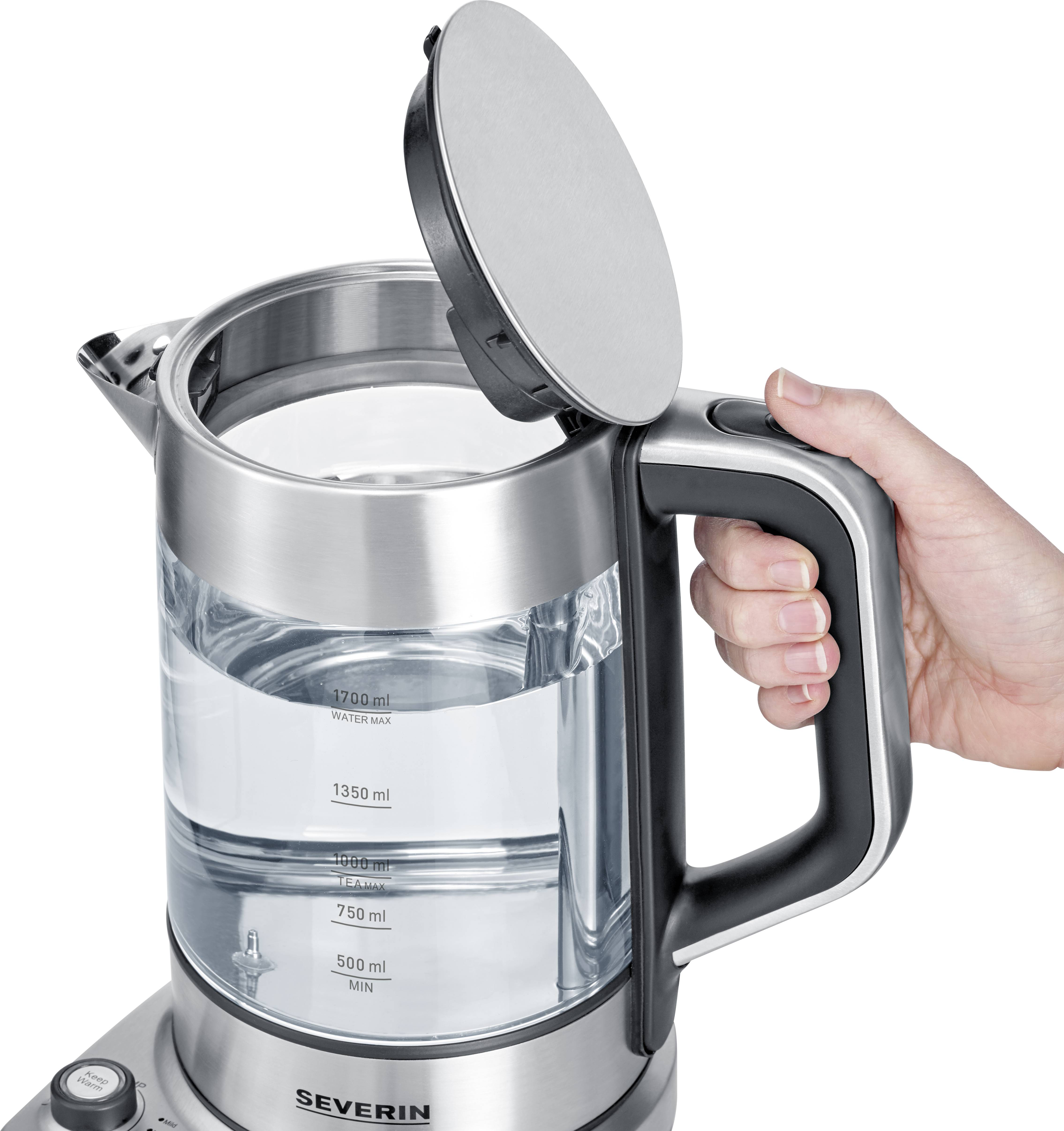 Eine Hand hält einen offenen, silbernen Wasserkocher aus Glas mit Wasserfüllstandsanzeige und Skala in Millilitern.