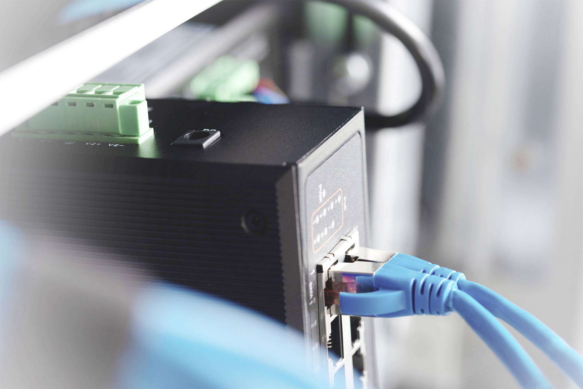 Netzwerkgerät mit mehreren eingesteckten blauen Ethernet-Kabeln, symbolisiert Konnektivität und Datenübertragung in einem Serverraum.