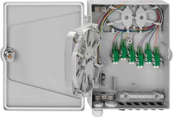 Ein grauer Verteilerkasten mit geöffnetem Deckel zeigt optische Anschlüsse und bunte Kabel, die in mehrere Ports eingesteckt sind.