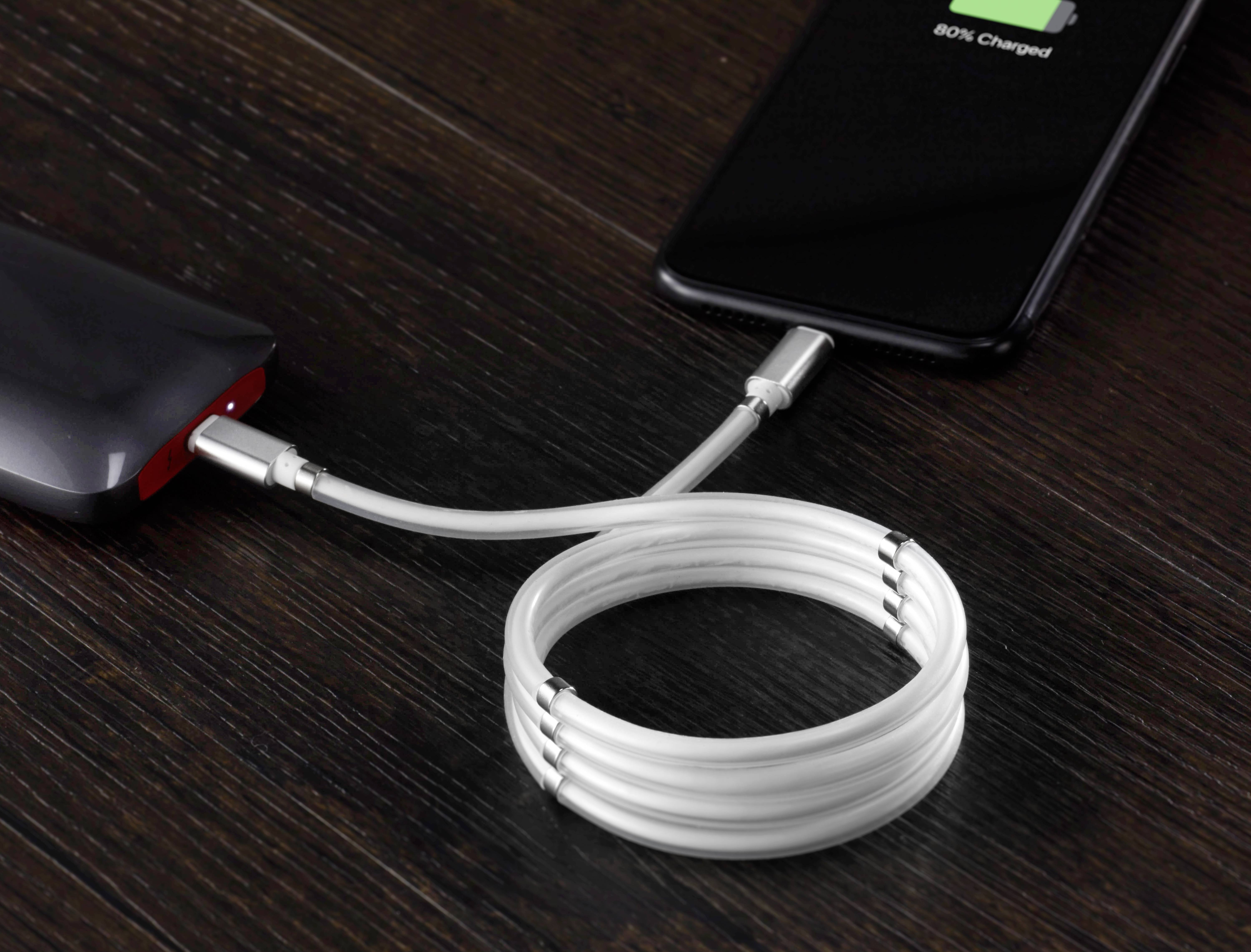 Ein Smartphone wird von einer Powerbank über ein USB-Kabel aufgeladen. Auf dem Bildschirm steht '80% geladen'.