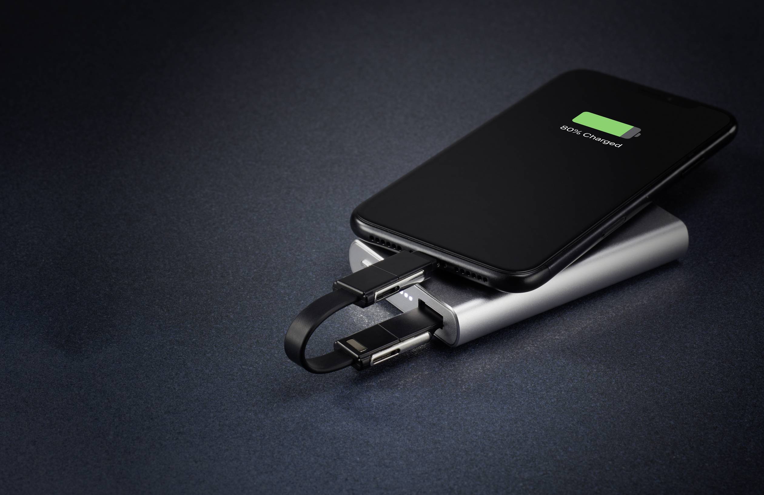 Ein Smartphone wird kabellos mit einem Akku aufgeladen. Es liegt auf einer Powerbank, die mit einem kurzen Kabel verbunden ist.