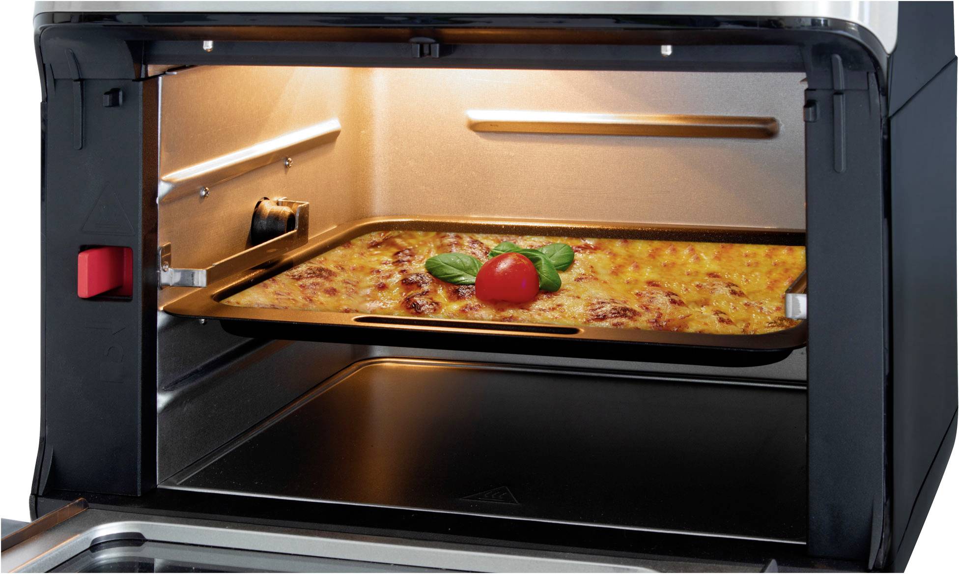 Eine Auflaufform mit Lasagne wird in einem beleuchteten Ofen gebacken. Oben auf der Lasagne liegt eine Tomate und Basilikumblätter.