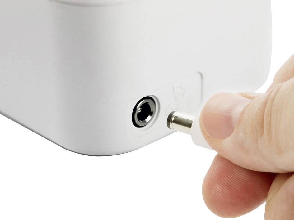 Hand steckt Stecker in einen weißen Adapter.