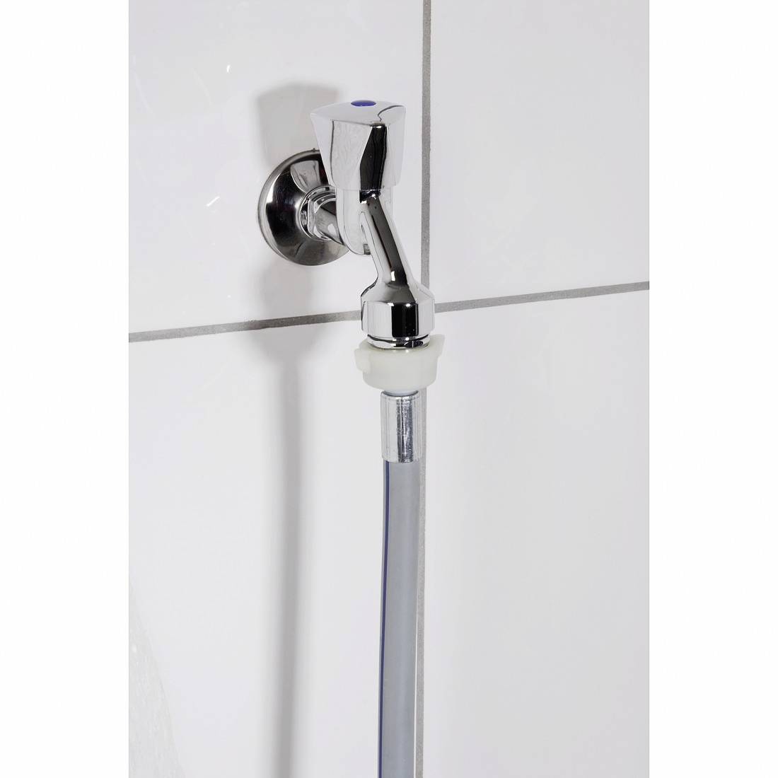 Ein glänzender Wasserhahn mit einem weißen Ring, befestigt an einer gefliesten Wand. Ein grauer Schlauch ist am Wasserhahn angebracht.