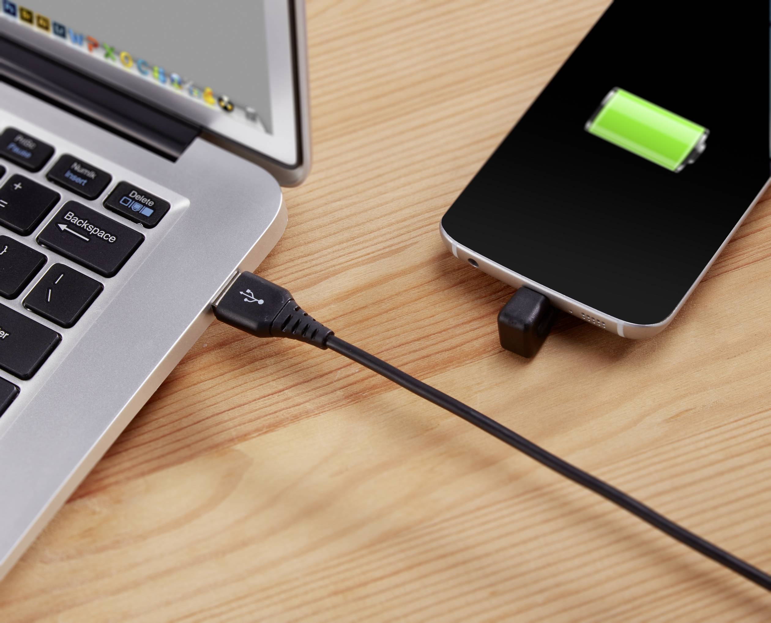 Smartphone wird über ein USB-Kabel an einem Laptop aufgeladen, grünes Batteriesymbol zeigt Ladestand an.