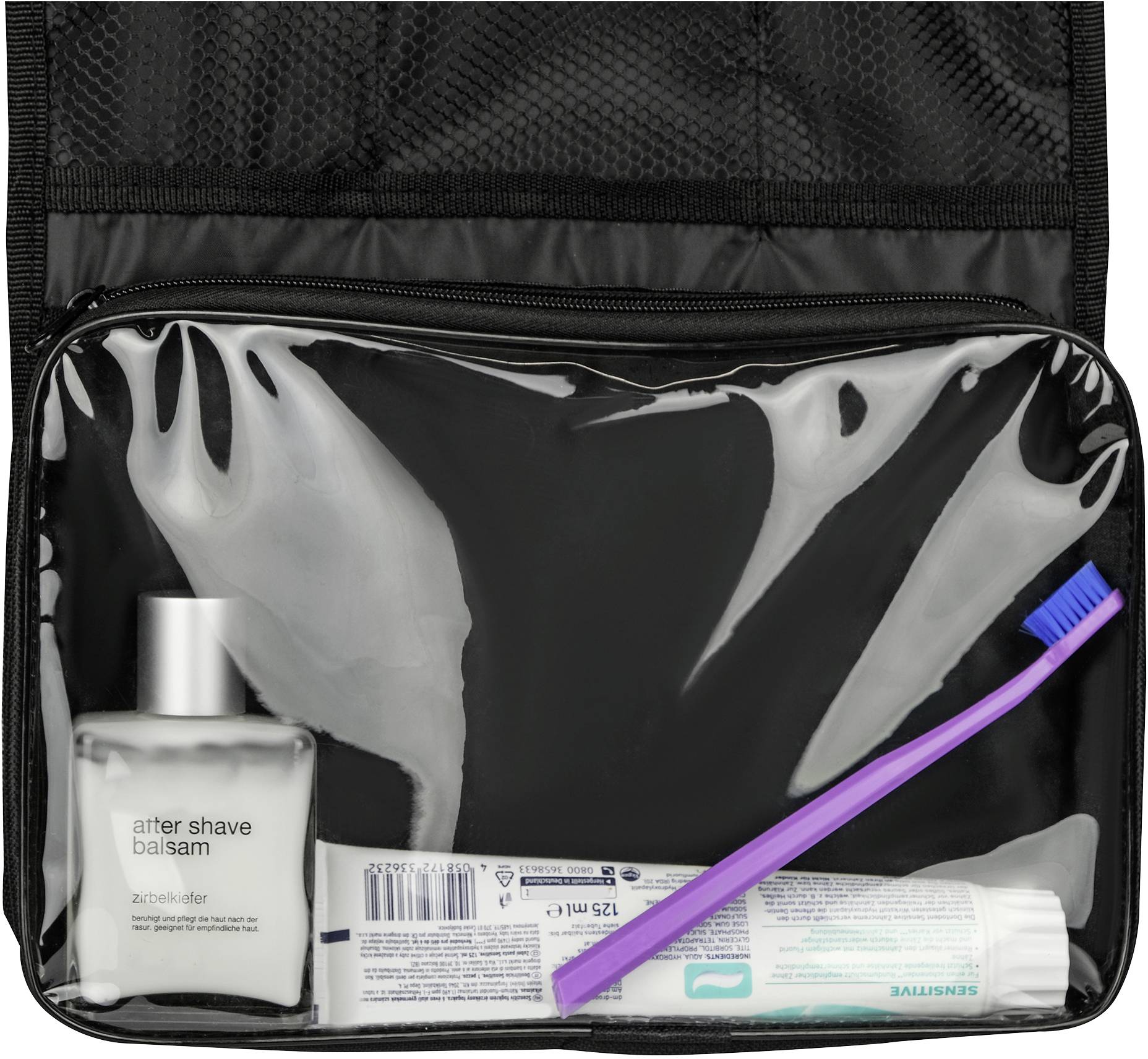 Rasierbalsamflasche, Zahnpasta-Tube und lila Zahnbürste in einer transparenten Kulturtasche.