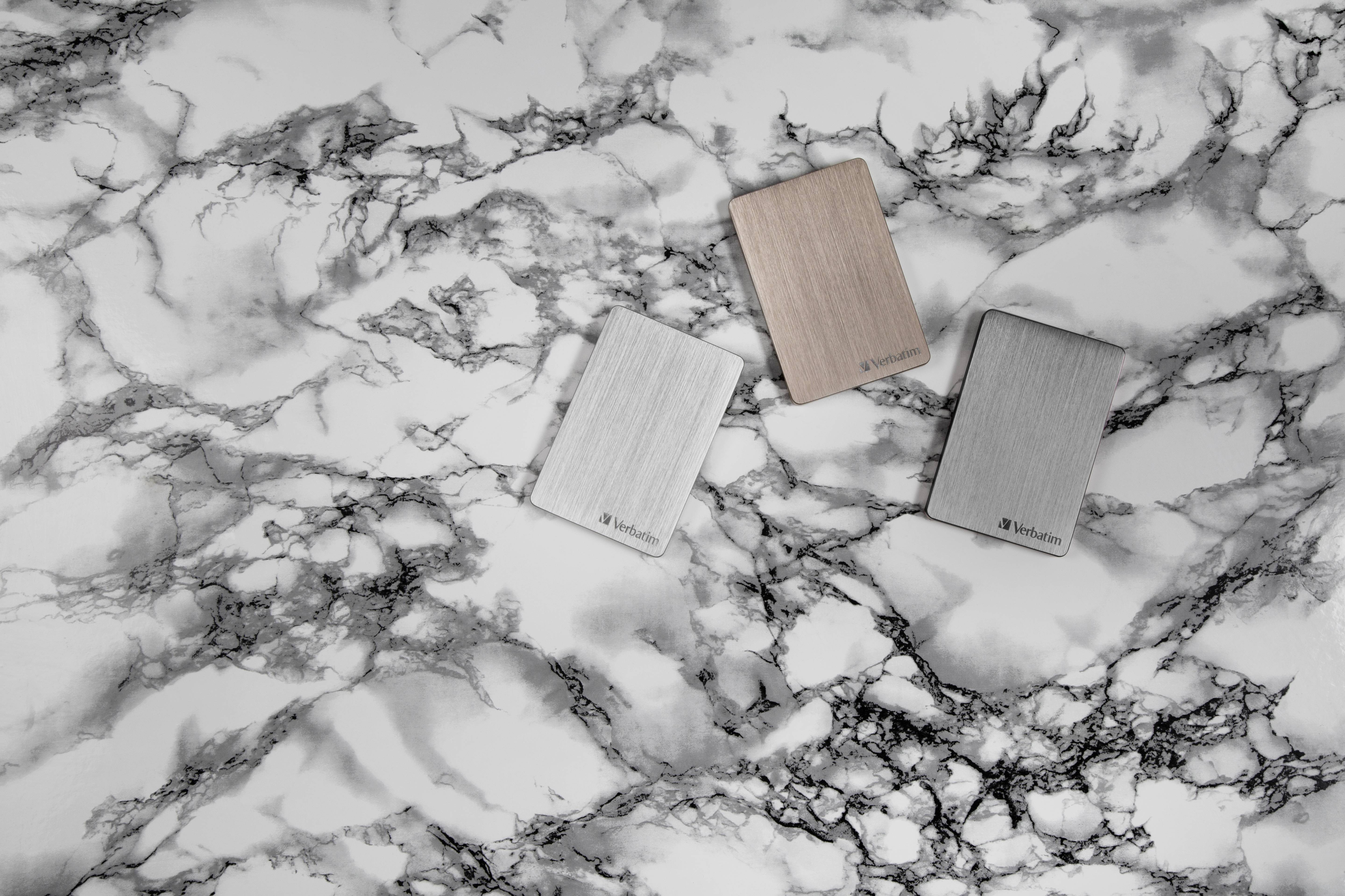 Drei externe Festplatten mit gebürsteter Metalloberfläche liegen auf einem marmorierten Hintergrund.