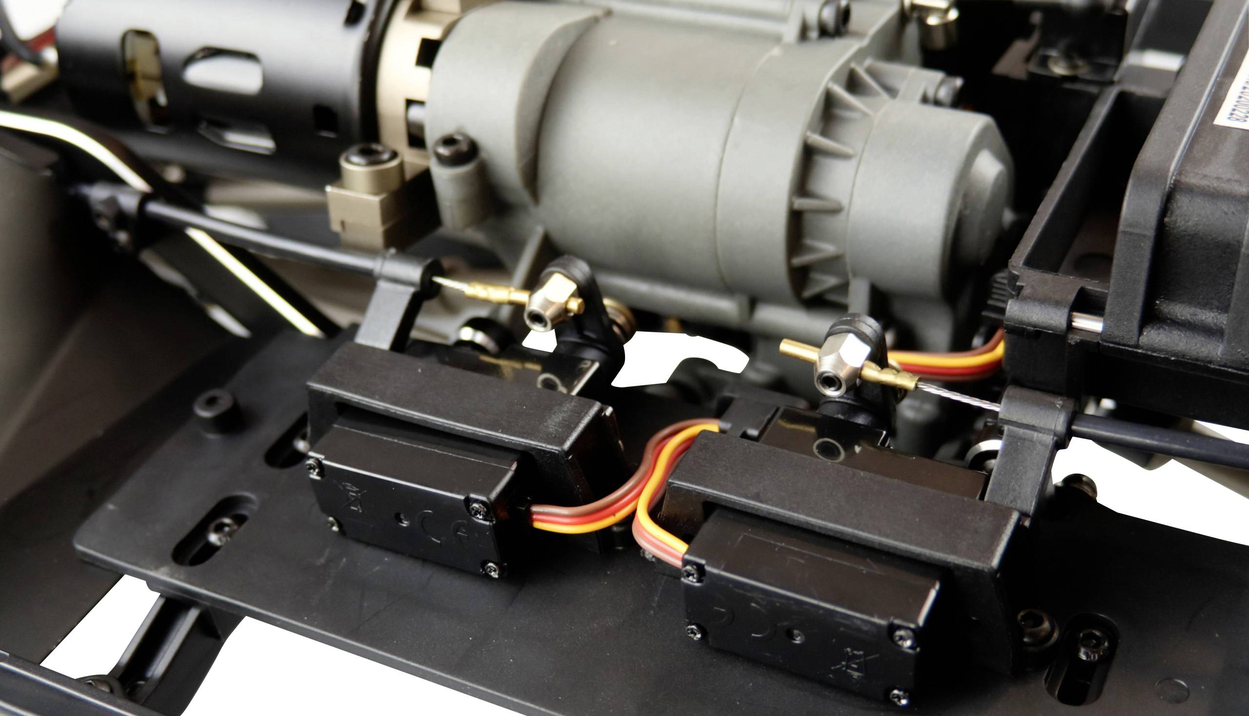 Nahaufnahme eines Modellbau-Servomotorsystems mit verbundenen Servos und Kabeln, montiert auf einer mechanischen Struktur.