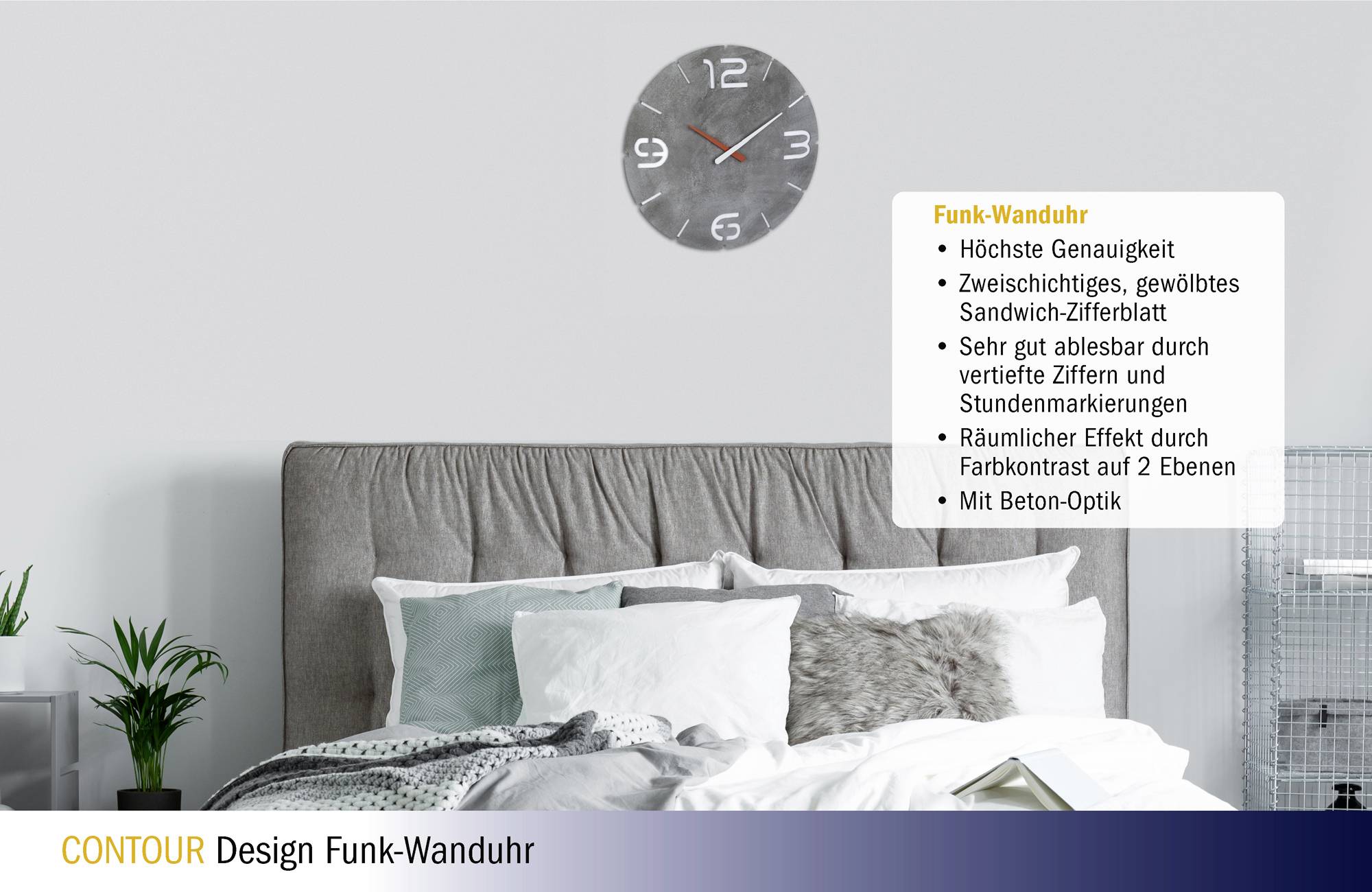 Ein Schlafzimmer mit einem Bett und mehreren Kissen. An der Wand hängt eine Funk-Wanduhr in Beton-Optik mit gut lesbaren Ziffern.