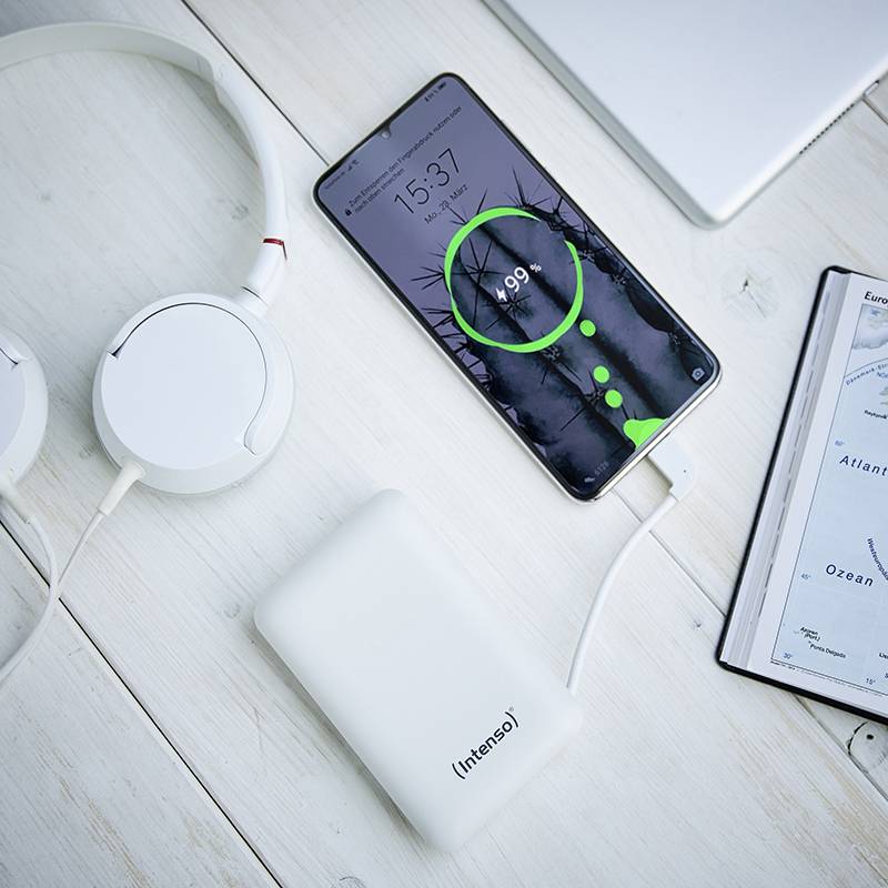 Smartphone mit grünem Ladebildschirm auf Tisch neben Kopfhörern, einer Powerbank und einem Notizbuch, das die Karte von Litauen zeigt.