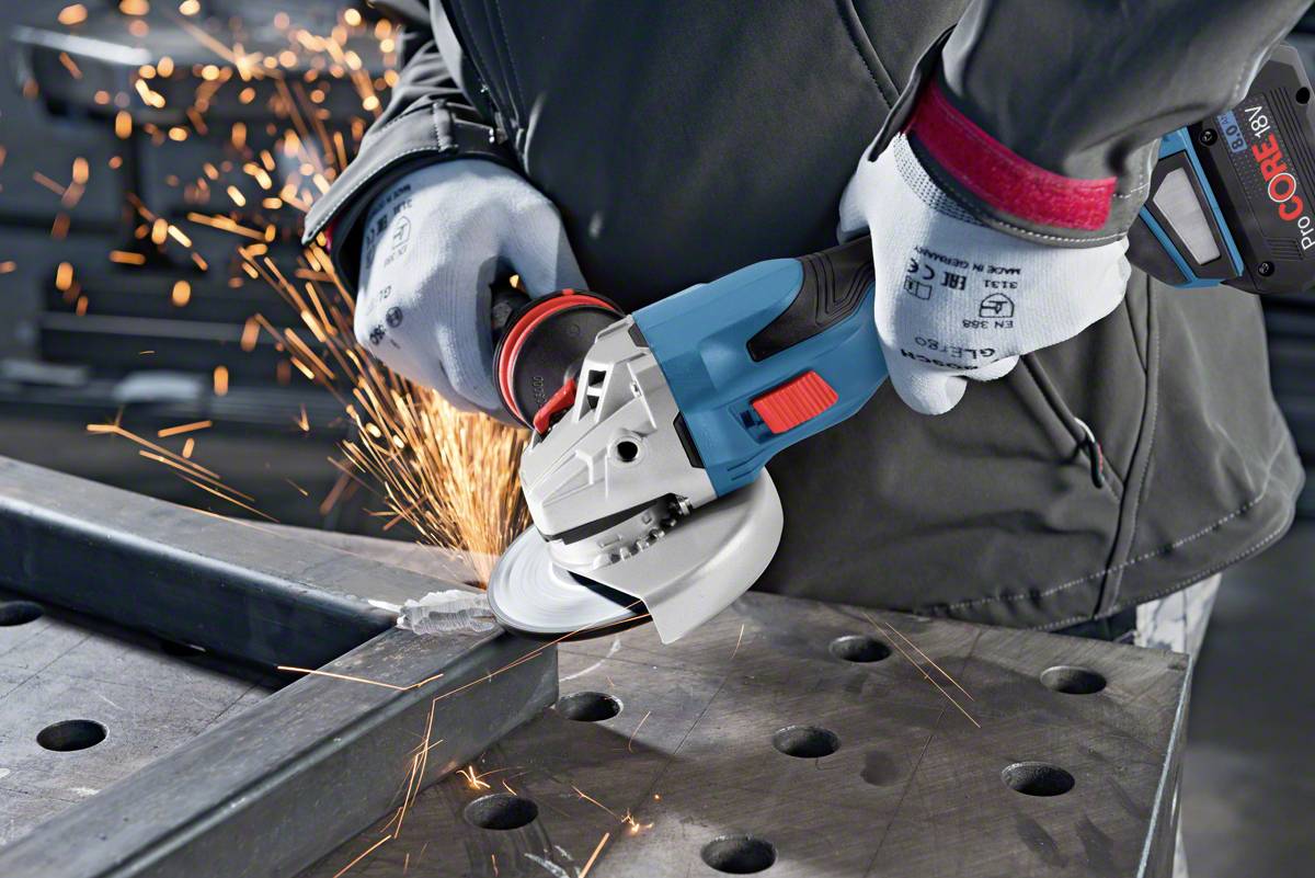 Person schleift Metall mit einem Winkelschleifer, Funken fliegen. Schutzhandschuhe und Schutzkleidung werden getragen.