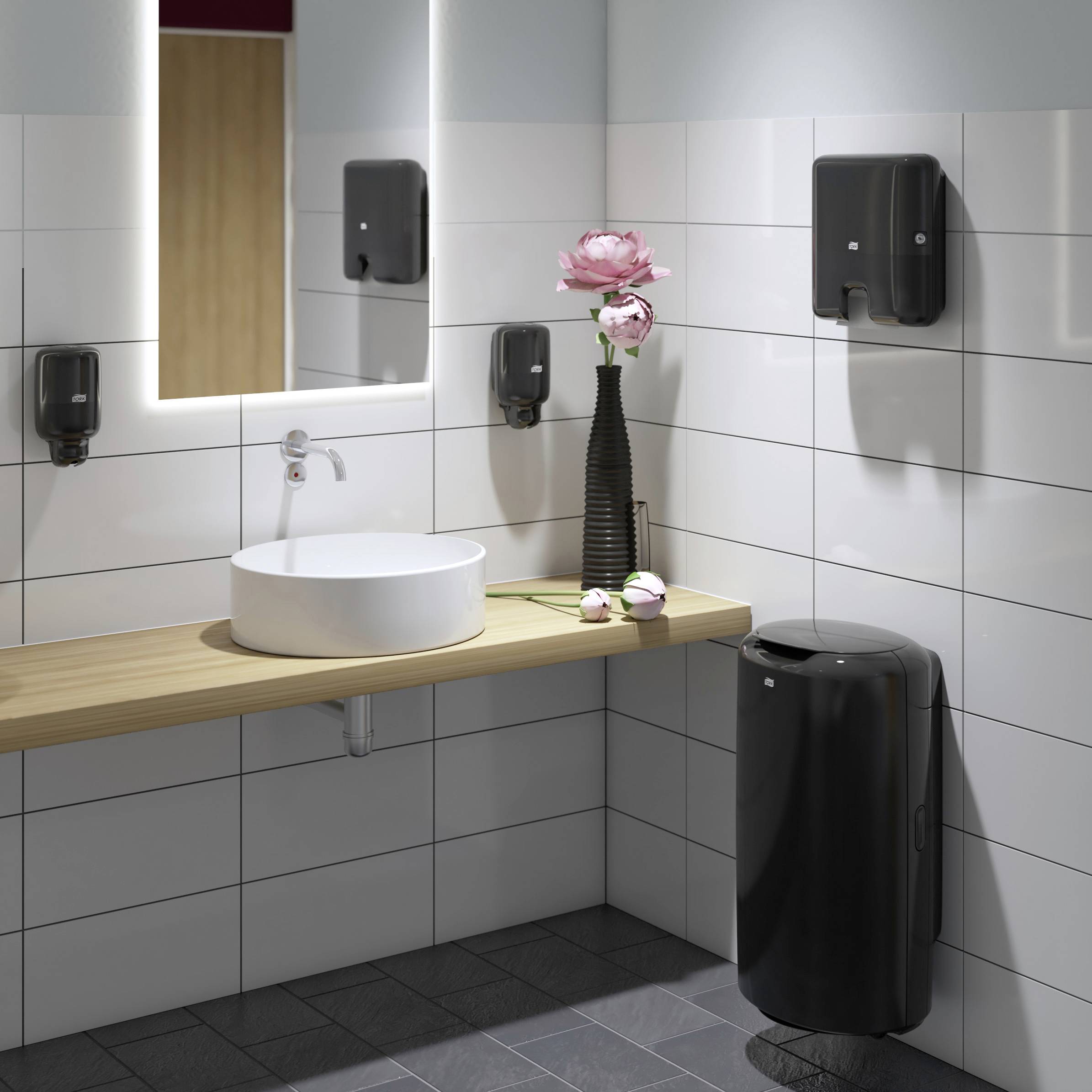 Modernes Badezimmer mit Waschbecken, Spiegel, Handtrockner und schwarzen Accessoires. Eine Vase mit rosa Blume steht auf der Ablage.