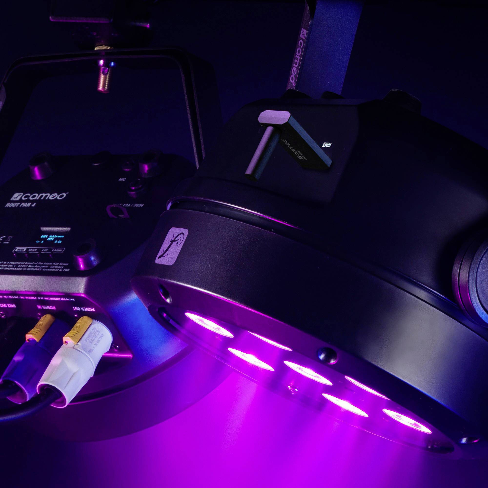Ein Scheinwerfer mit mehreren lila LED-Leuchten, montiert an einem Metallrahmen, strahlt helles Licht aus.