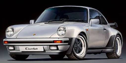 Ein silbernes Auto, Porsche 911 Turbo, mit breiten Kotflügeln und charakteristischem Heckspoiler, steht vor dunklem Hintergrund.