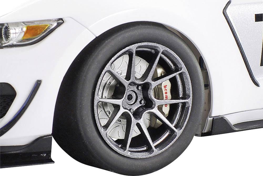 Nahaufnahme eines Autoreifens eines weißen Rennwagens mit silbernen Felgen und sichtbarer Bremse. Rennsportkontext.