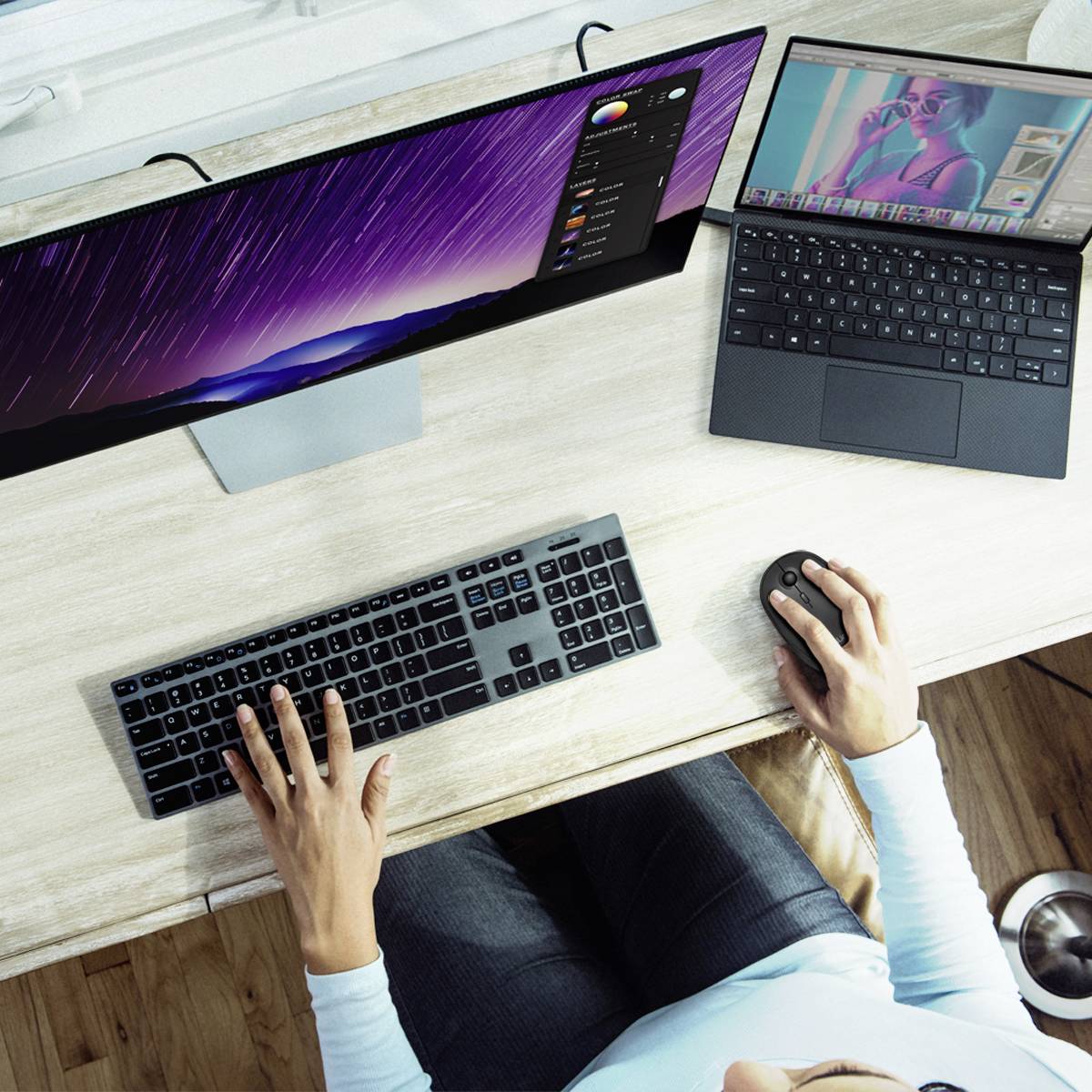 Eine Person arbeitet an einem Schreibtisch mit zwei Monitoren; der eine zeigt ein Foto mit Bildbearbeitungssoftware, der andere einen Browser.