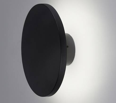 Runde schwarze Wandleuchte mit indirektem Lichtschein, der einen sanften weißen Halo auf der Wand erzeugt.
