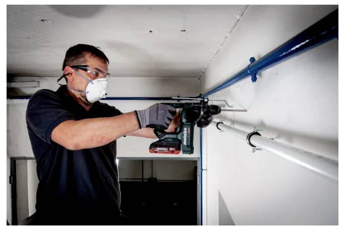 Eine tragbare Kabelrolle mit Griff, die drei rote Steckdosen auf einer schwarzen kreisförmigen Trommel und ein aufgerolltes schwarzes Kabel aufweist, entwickelt für elektrische Zwecke.