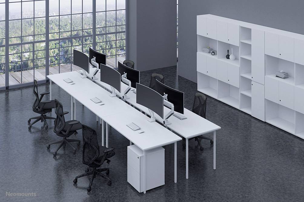 Moderner Büroraum mit langen Schreibtischen, ergonomischen Stühlen und mehreren Computermonitoren. Große Fenster mit Blick auf Wälder.