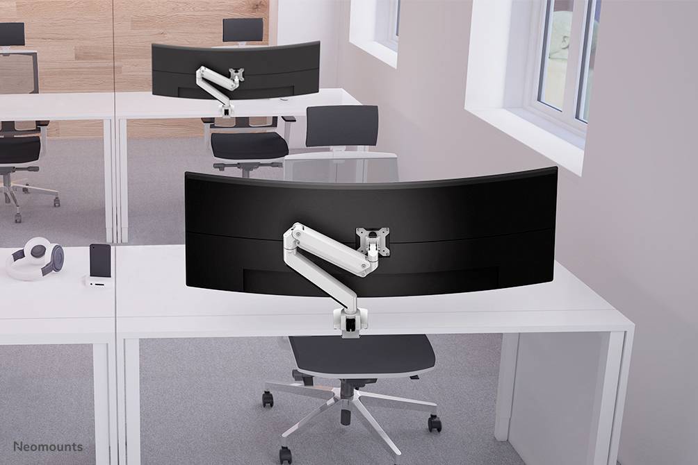 Zwei moderne Büros mit großen, gebogenen Monitoren auf weißen Schreibtischen vor hellen Fenstern. Monitorarme sind flexibel verstellbar.