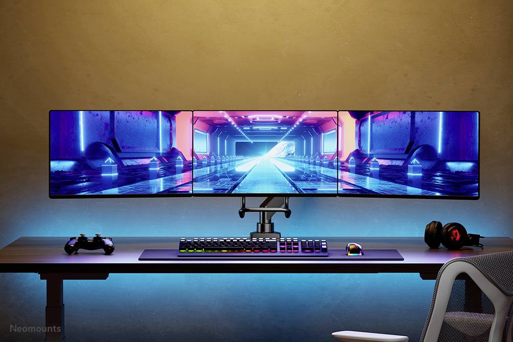 Drei Monitore auf Schreibtisch zeigen futuristische Tunnel-Animation. Darunter Tastatur und Controller. Modernes Gaming-Setup.