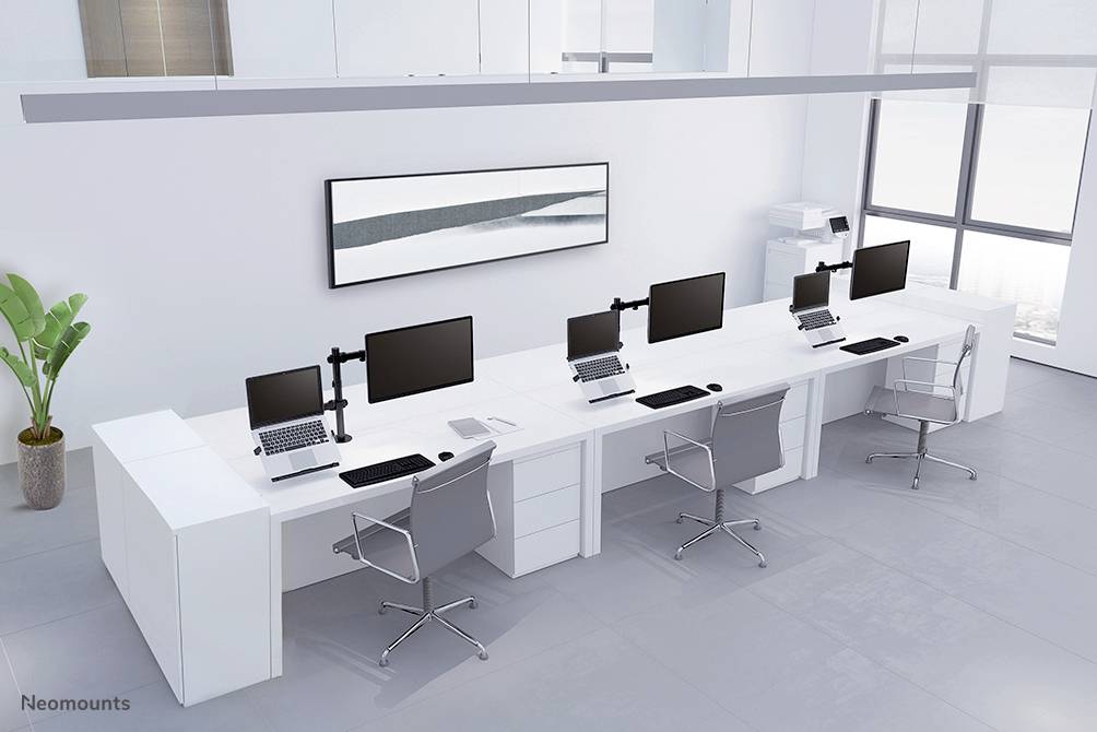 Ein modernes, minimalistisches Büro mit vier Arbeitsplätzen. Jeder Arbeitsplatz hat einen Bildschirm, Laptop und Bürostuhl. Im Hintergrund ist ein Drucker.