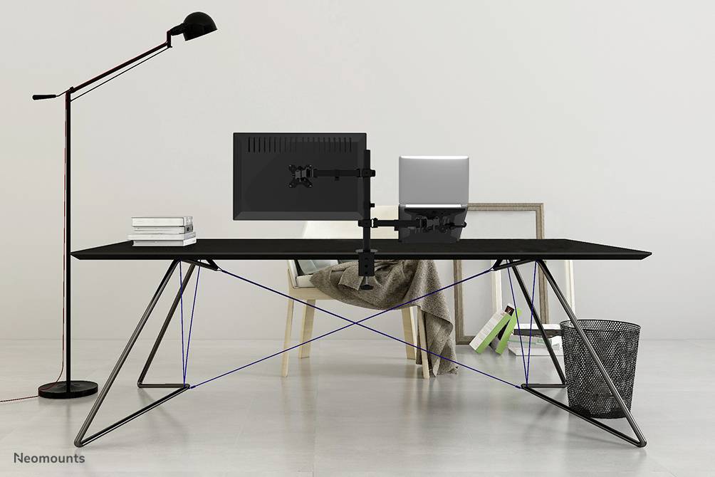 Ein moderner Schreibtisch mit einem Monitor, einem Laptop, Büchern und einer Stehlampe. Im Hintergrund ein Stuhl und ein Papierkorb.