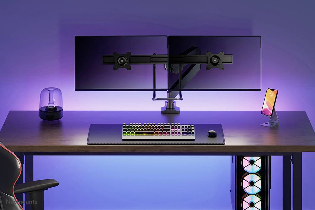 Ein moderner Arbeitsplatz mit zwei Monitoren auf einem Schreibtisch, einer RGB-Tastatur und einem Smartphone in einem Halter; klare und organisierte Anordnung.