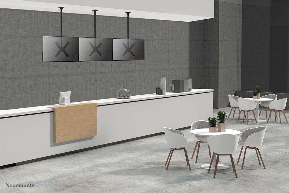 Ein moderner Cafébereich mit einem langen Tresen, auf dem sich Bildschirme befinden. Im Vordergrund stehen runde Tische mit weißen Stühlen.