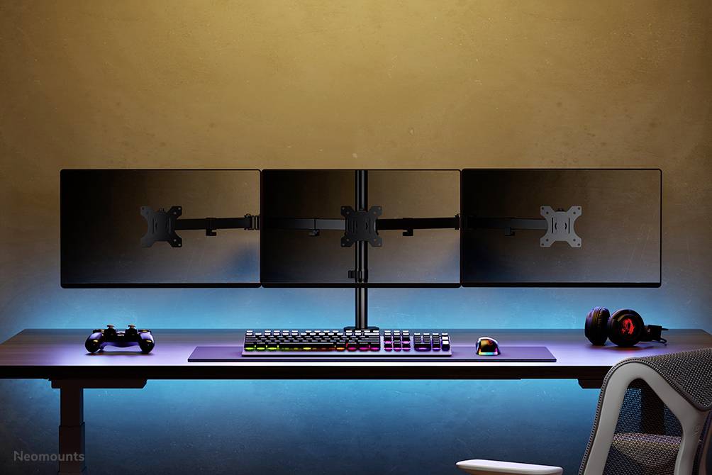 Drei Monitore auf einem Schreibtisch mit Gaming-Zubehör, darunter Tastatur, Maus, Headset und Controller; blauer LED-Hintergrund.