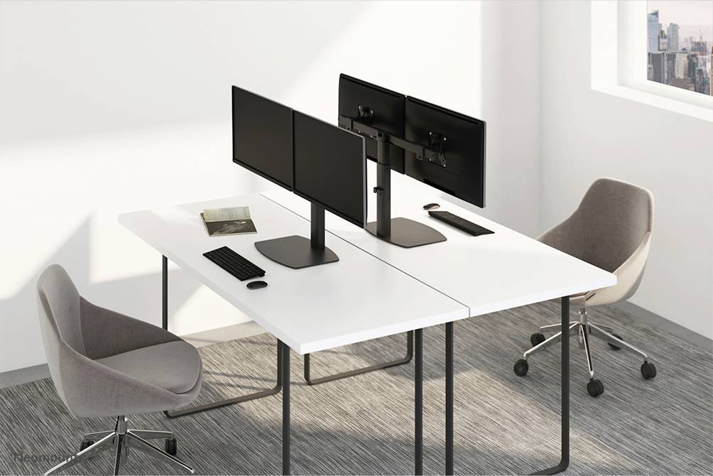 Ein modernes Büro mit zwei weißen Schreibtischen, jeweils mit zwei Monitoren. Zwei graue Stühle stehen an den Schreibtischen.