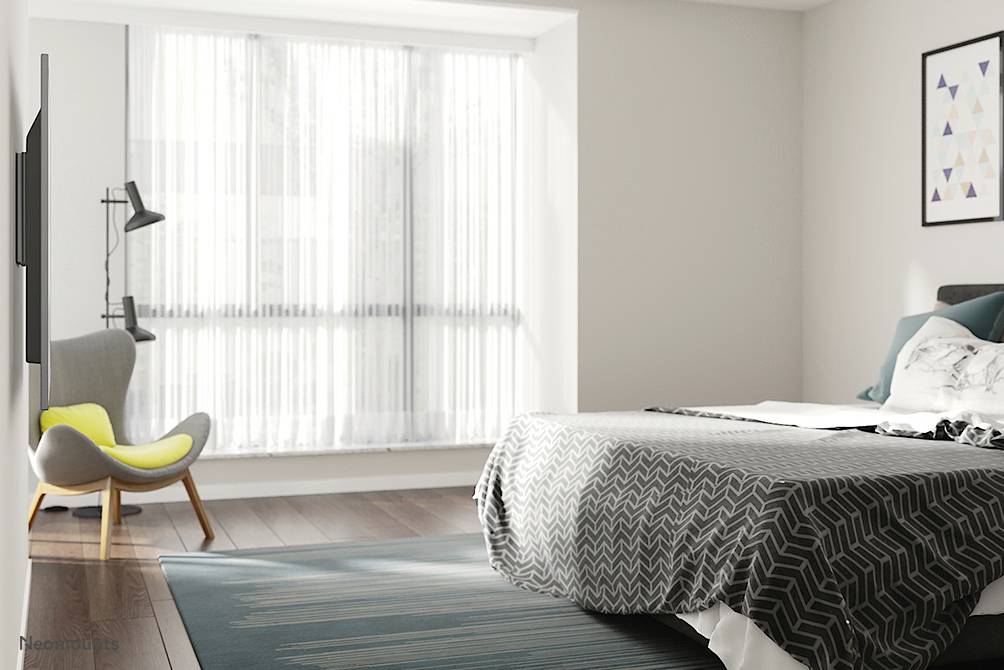 Ein modernes Schlafzimmer mit einem großen Fenster, grauen Bettüberzug, einem Sessel neben einer Stehlampe und einem Bild an der Wand.