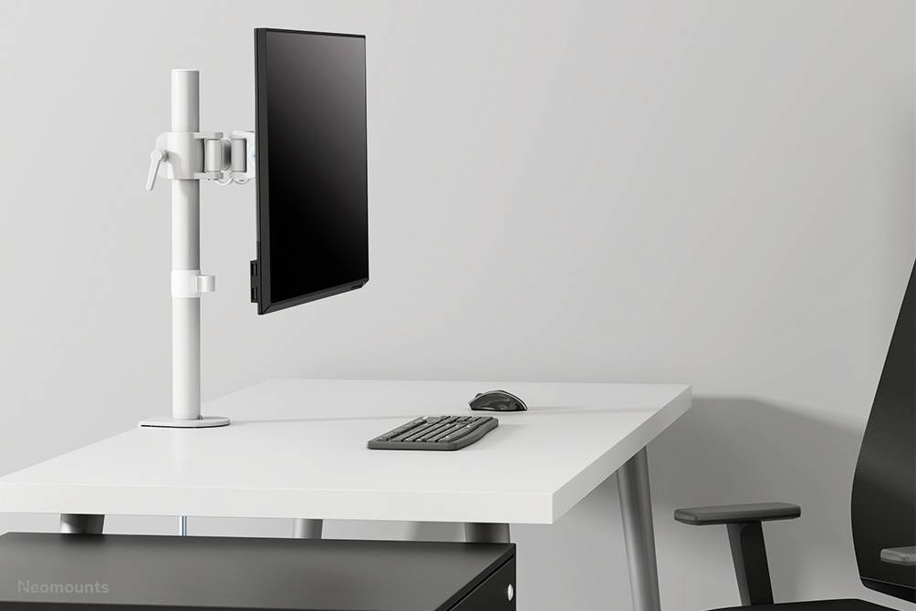 Ein leeres Büro mit weißem Schreibtisch, einem Monitorhalter, Monitor, Tastatur und Maus. Ein schwarzer Bürostuhl steht daneben.